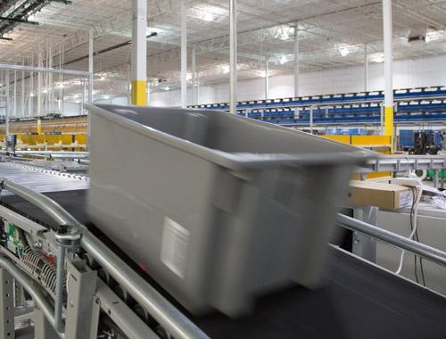 A container is transported on an automated line while an optical sensor tracks its progress.